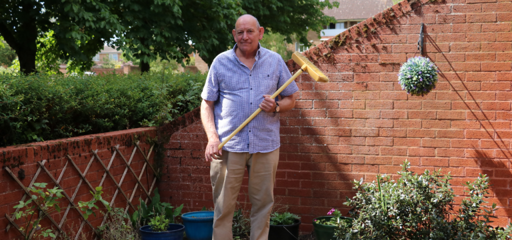 Hospice Neighbour volunteer standing with broom in garden