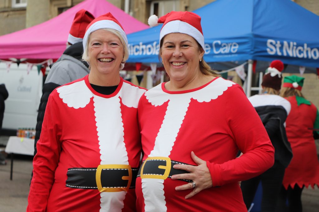 Two Festive Fun Run participants dressed in Santa suits smiling at the camera