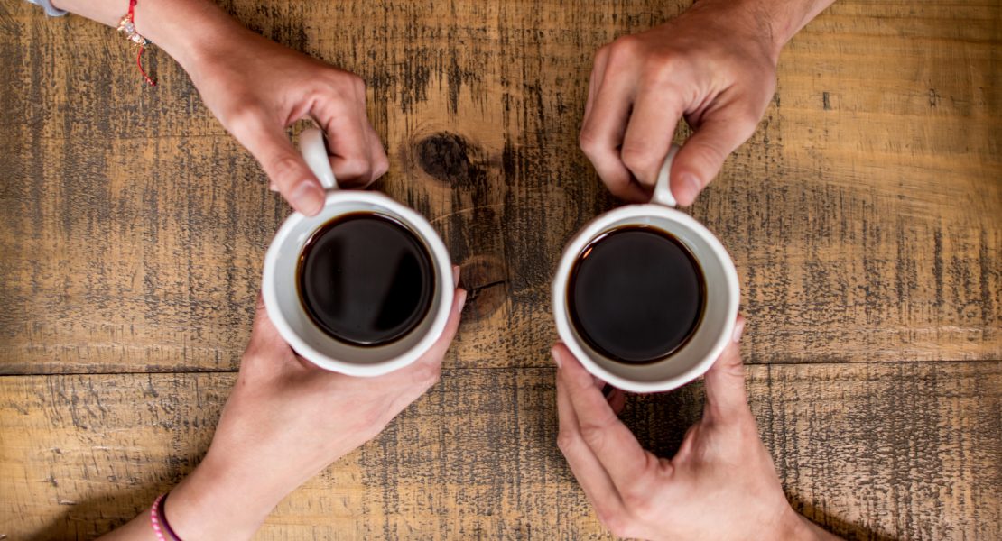 Two people facing each other drinking coffee