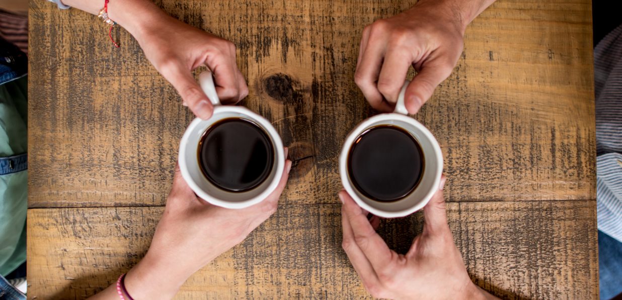 Two people facing each other drinking coffee
