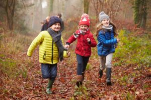 Three children running happily through a forest