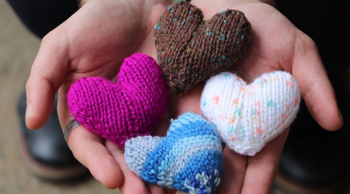 Knitted hearts presented in hands
