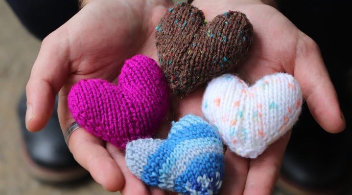 Knitted hearts presented in hands