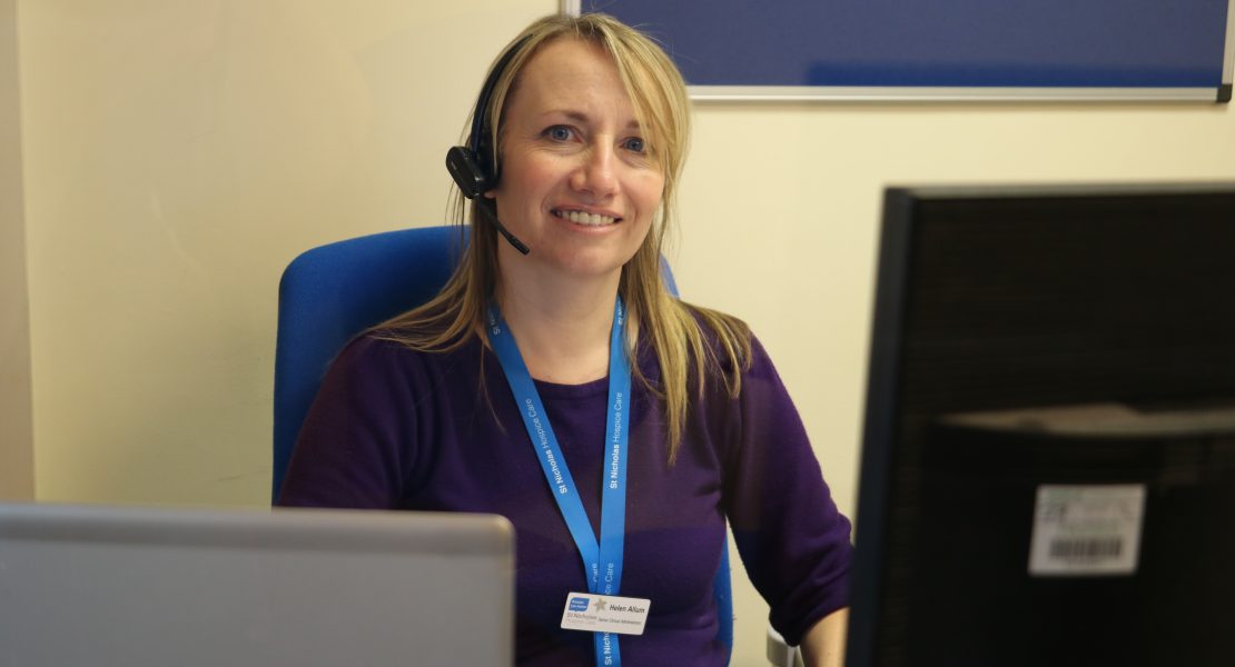 hospice staff member wearing headset sat behind computer screens