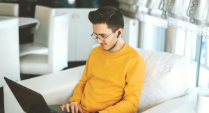 man sitting on sofa using laptop