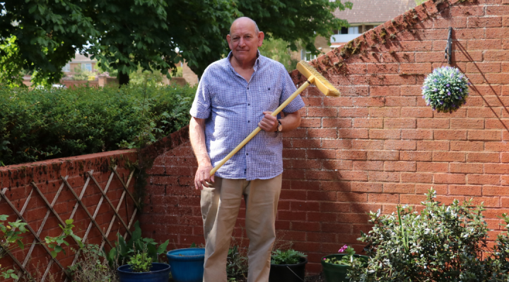 Hospice Neighbour volunteer standing with broom in garden