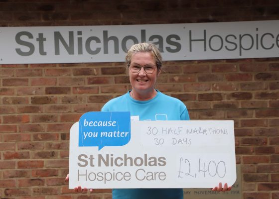 Image of Melanie Furness holding a cheque in celebration of her efforts for St Nicholas Hospice Care