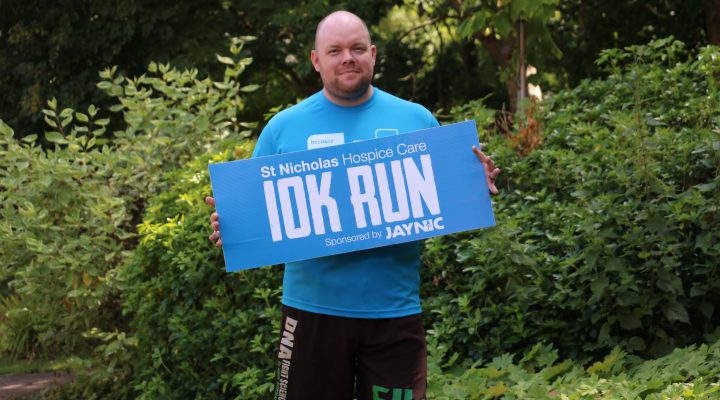 Hospice Fundraiser Lee Graham holding a sign advertising that he will be taking place in the Hospice's 10K event