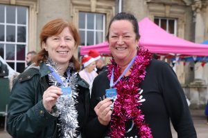 Tinsel-clad Festive Fun Run participants holding their medals