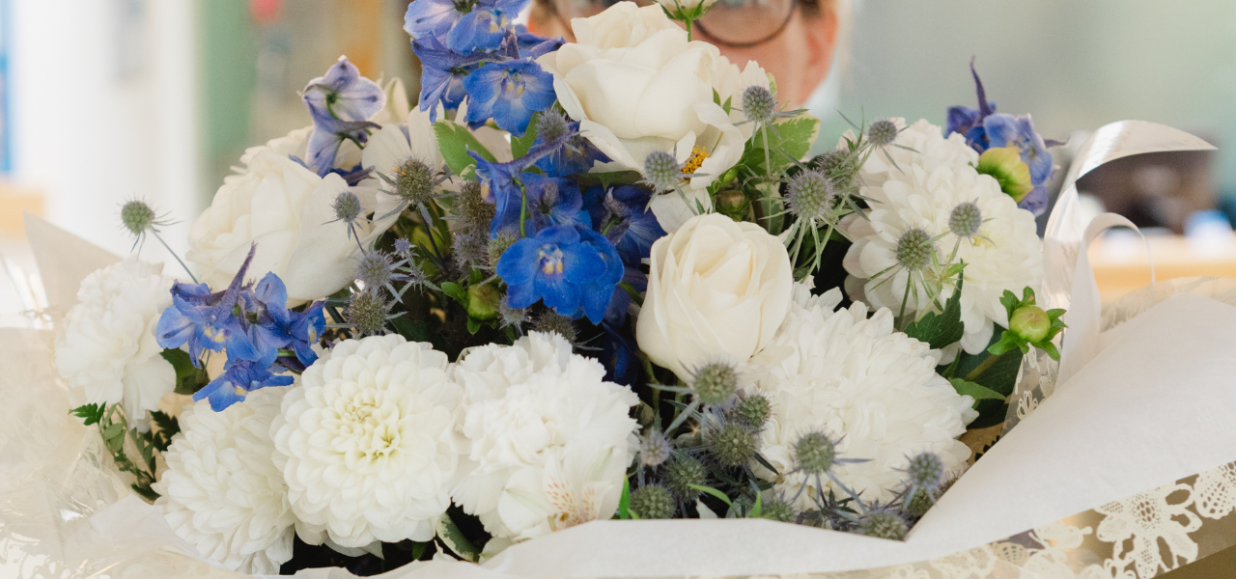 A Hospice staff member holding a large bunch of white and blue flowers