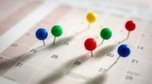 A close up image of a calendar with pins in some of the dates