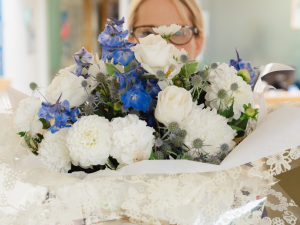 A Hospice staff member holding a large bunch of white and blue flowers