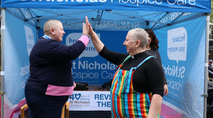 Two reverends doing a high five after having their heads shaved for charity