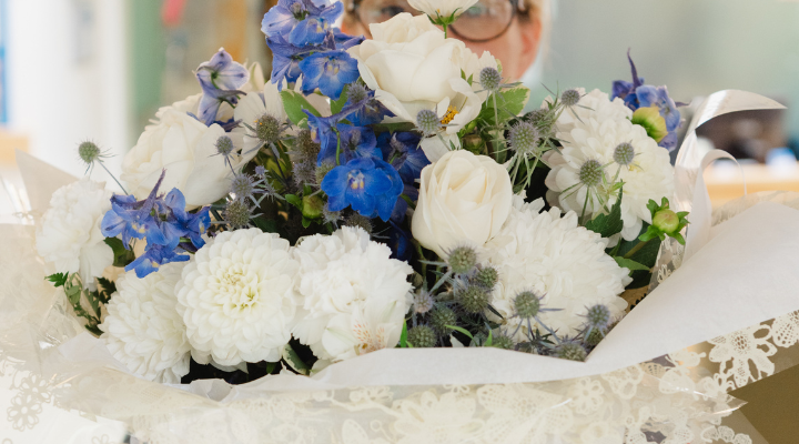 A Hospice staff member holding a large bunch of white and blue flowers