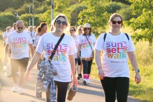 A group of smiling Sunset Walk participants along the route wearing event T-shirts