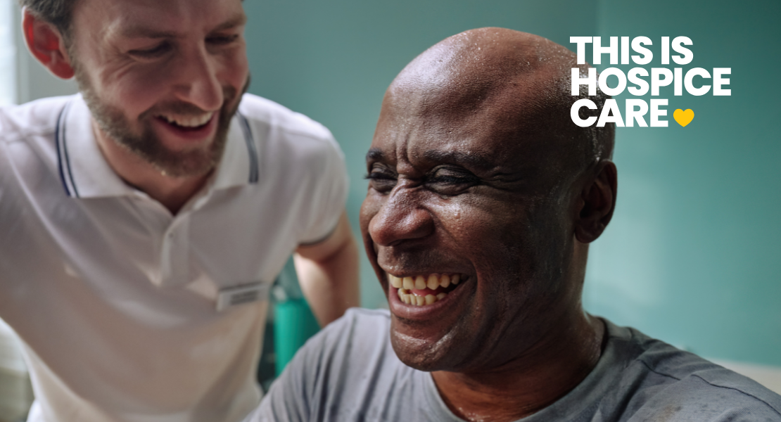 A man smiling in a gym whilst being supported by a physiotherapist