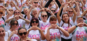 Crowd of smiling Sunset Walk participants wearing Sunset Walk t-shirts and making heart shapes with their hands