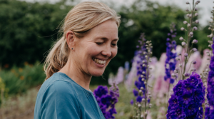 Photo of Clare Foster smiling surrounded by flowers