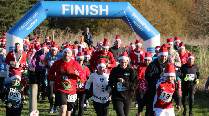 crowd of runners in festive fancy dress and santa hats with the start line in the background