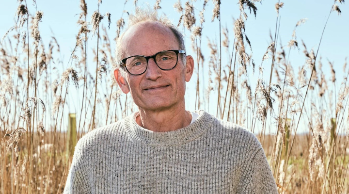 Photo of Tom Hoblyn smiling against a backdrop of reeds and blue sky