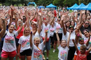Crowd of Sunset Walk participants with arms in the air