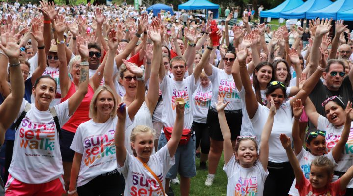 Crowd of Sunset Walk participants with arms in the air