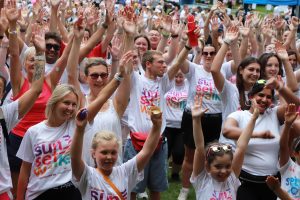 Crowd of Sunset Walk participants with arms in the air